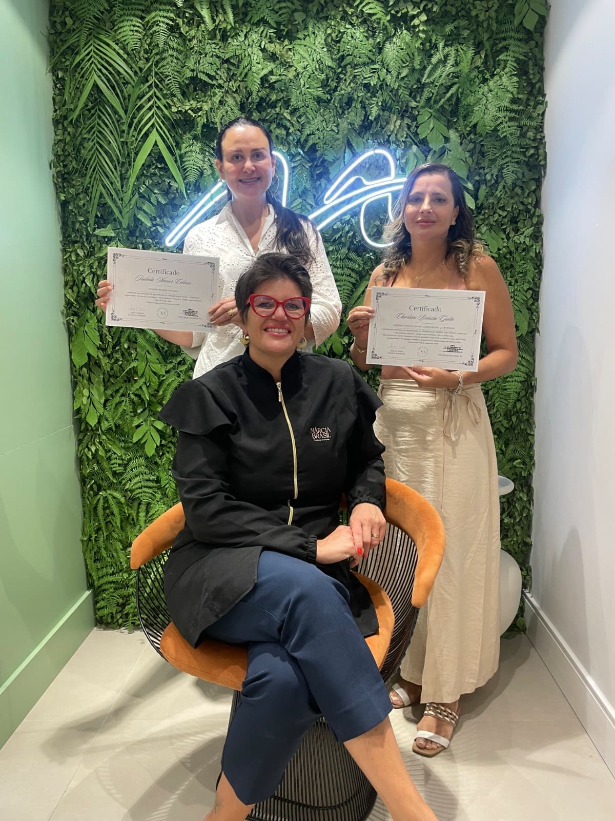 Márcia Brasil com duas alunas segurando seus certificados